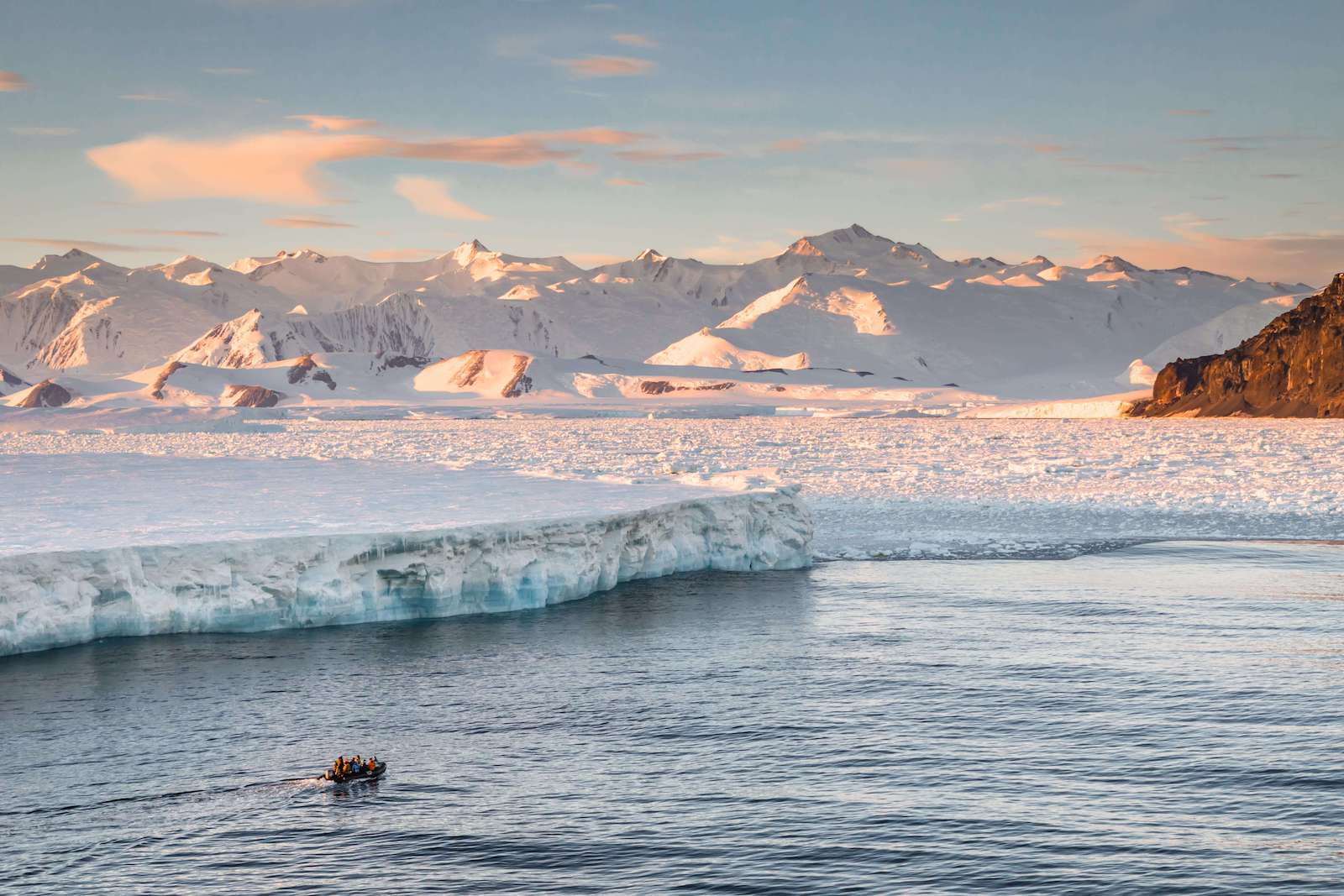 Image of large ice shelf in front of snow-covered mountains