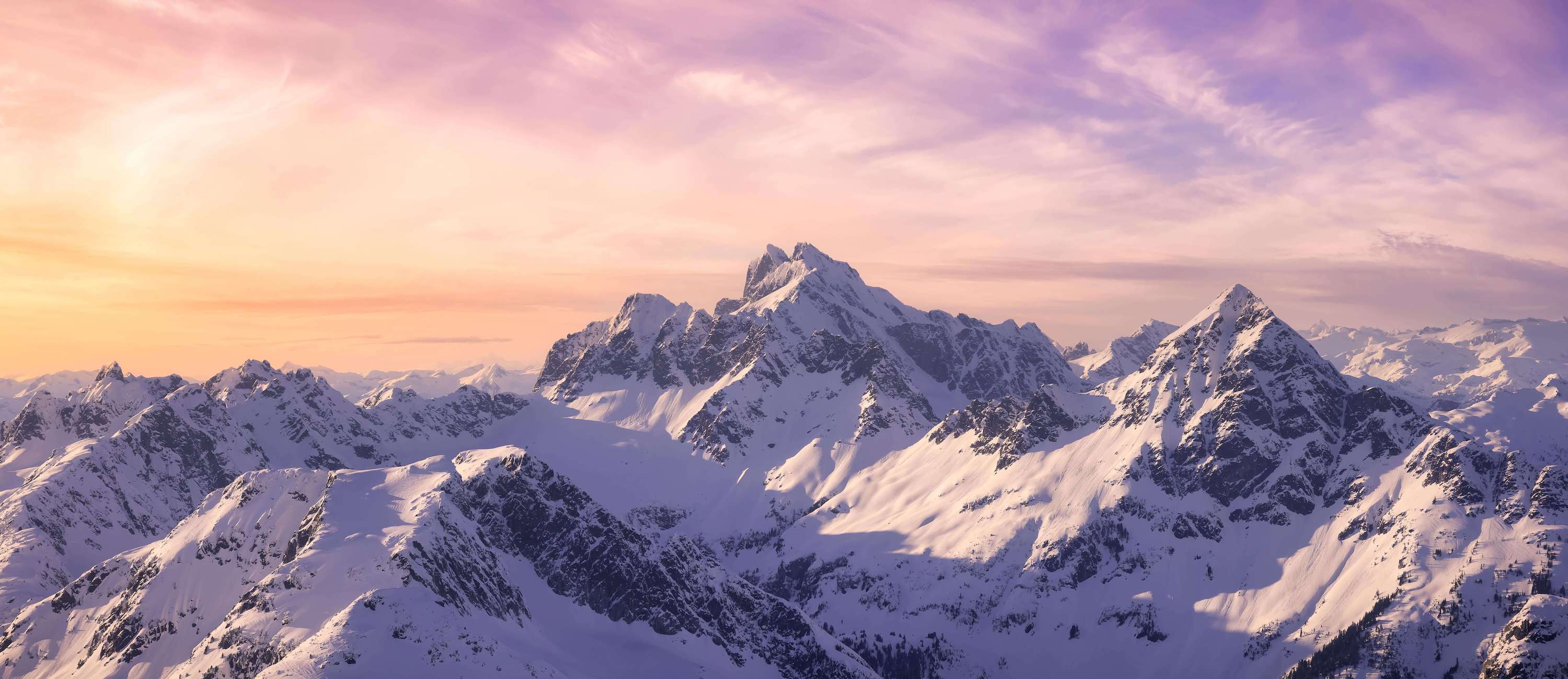 Image of wispy clouds over snow-covered rocky mountain tops